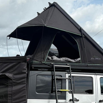 Black rooftop tent on a vehicle with a cloudy sky background