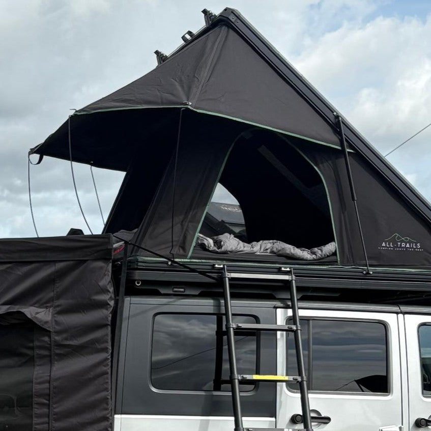Black rooftop tent on a vehicle with a cloudy sky background