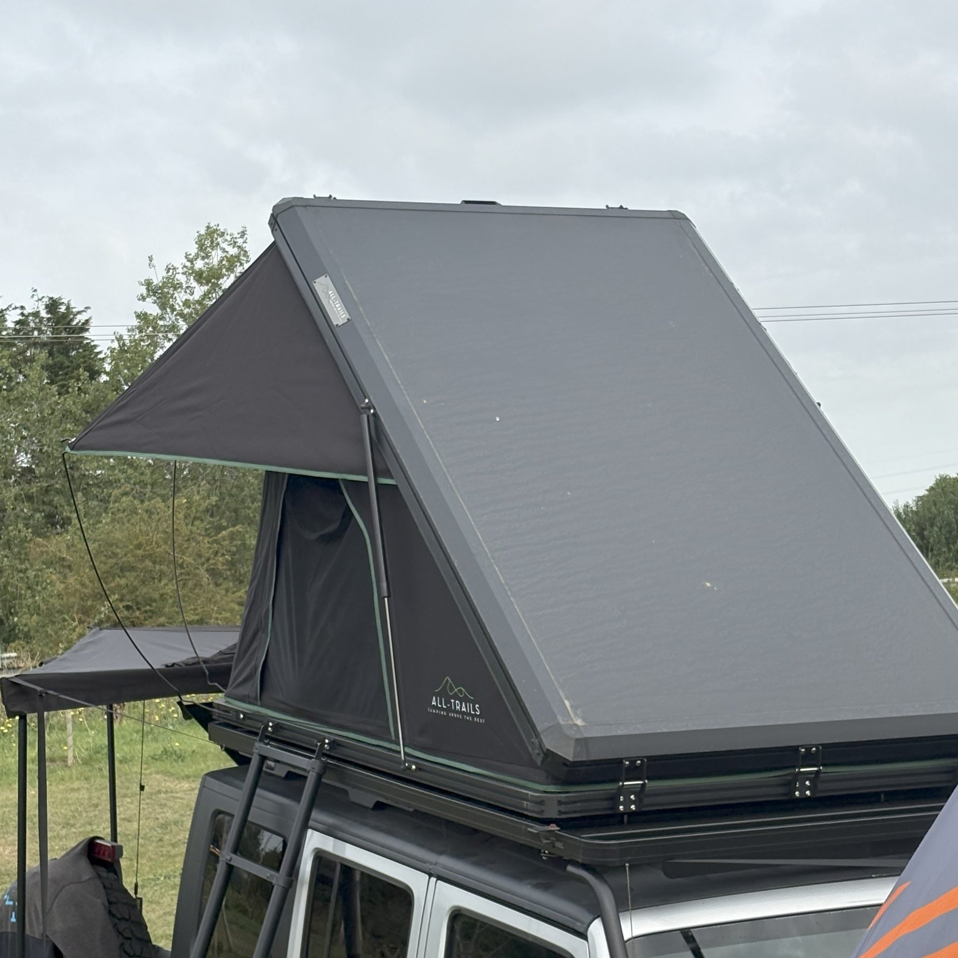 Roof top tent attached to a vehicle with trees in the background