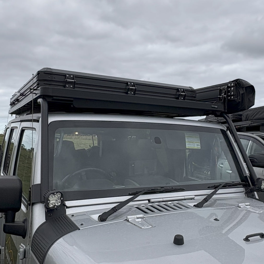 Roof top tent with 'All-Trails' branding from Trail4.com against a cloudy sky